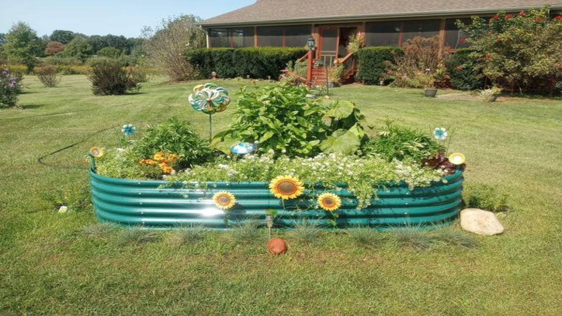  Garden bed with sunflowers, herbs, and decorative items on grassy lawn.